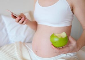 gravida comendo enquanto verifica celular