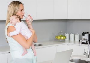 Mãe segurando bebe enquanto toma água